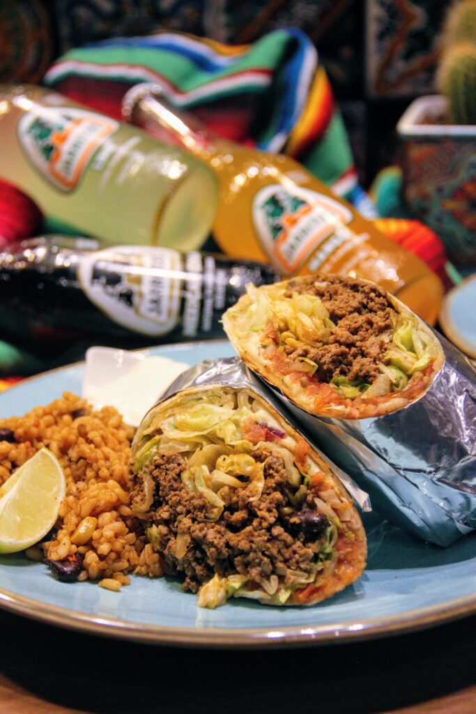 zdjęcie burrito na talerzu w tle z napojem marki Jarritos